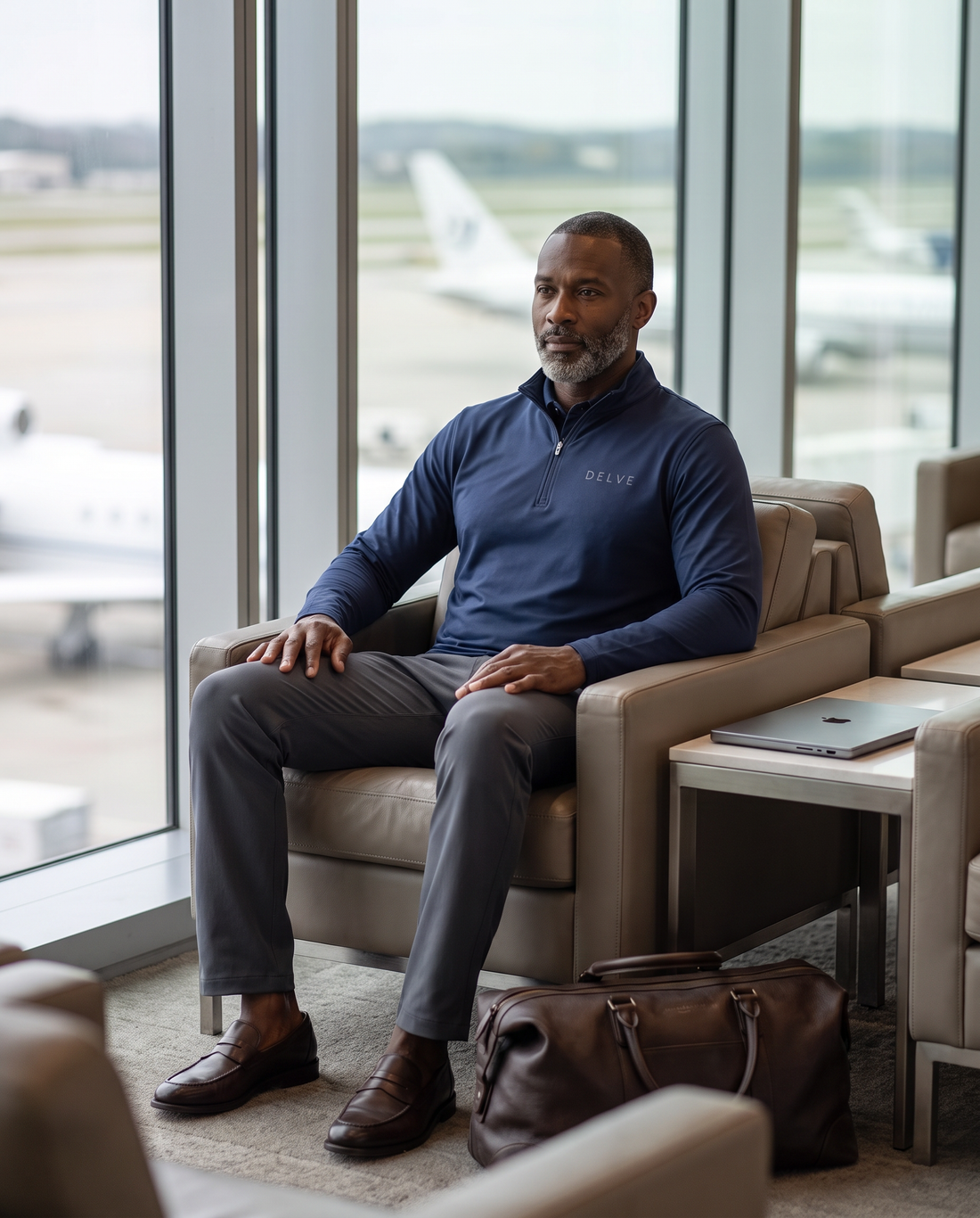 Charcoal technical chinos and a navy quarter-zip in an airport lounge