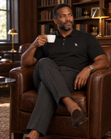 Man in a leather club chair in a private library wearing the black Standup Polo