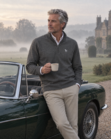 Man beside a vintage convertible on a country estate wearing the dark grey Commit Quarter-Zip