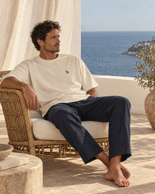 Man relaxing on a coastal villa veranda wearing the ecru Heavyweight TT Tee