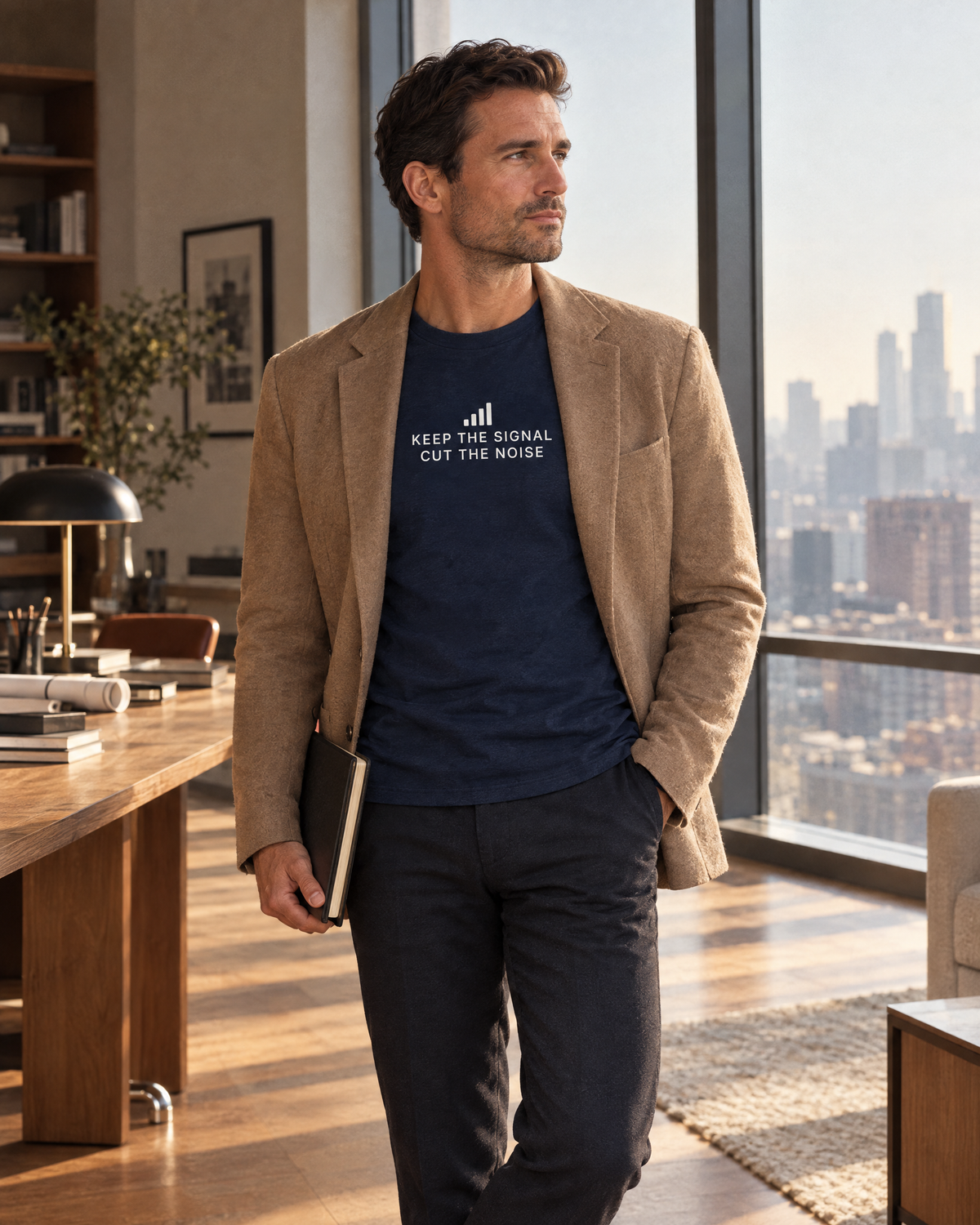 Man in a city loft study wearing the navy Keep the Signal Tee under a camel blazer