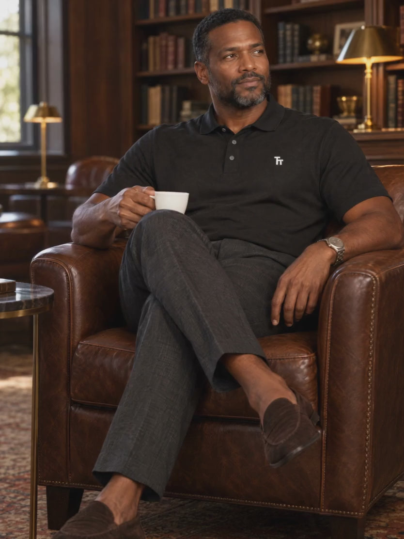 The Standup Polo in black, worn with charcoal trousers