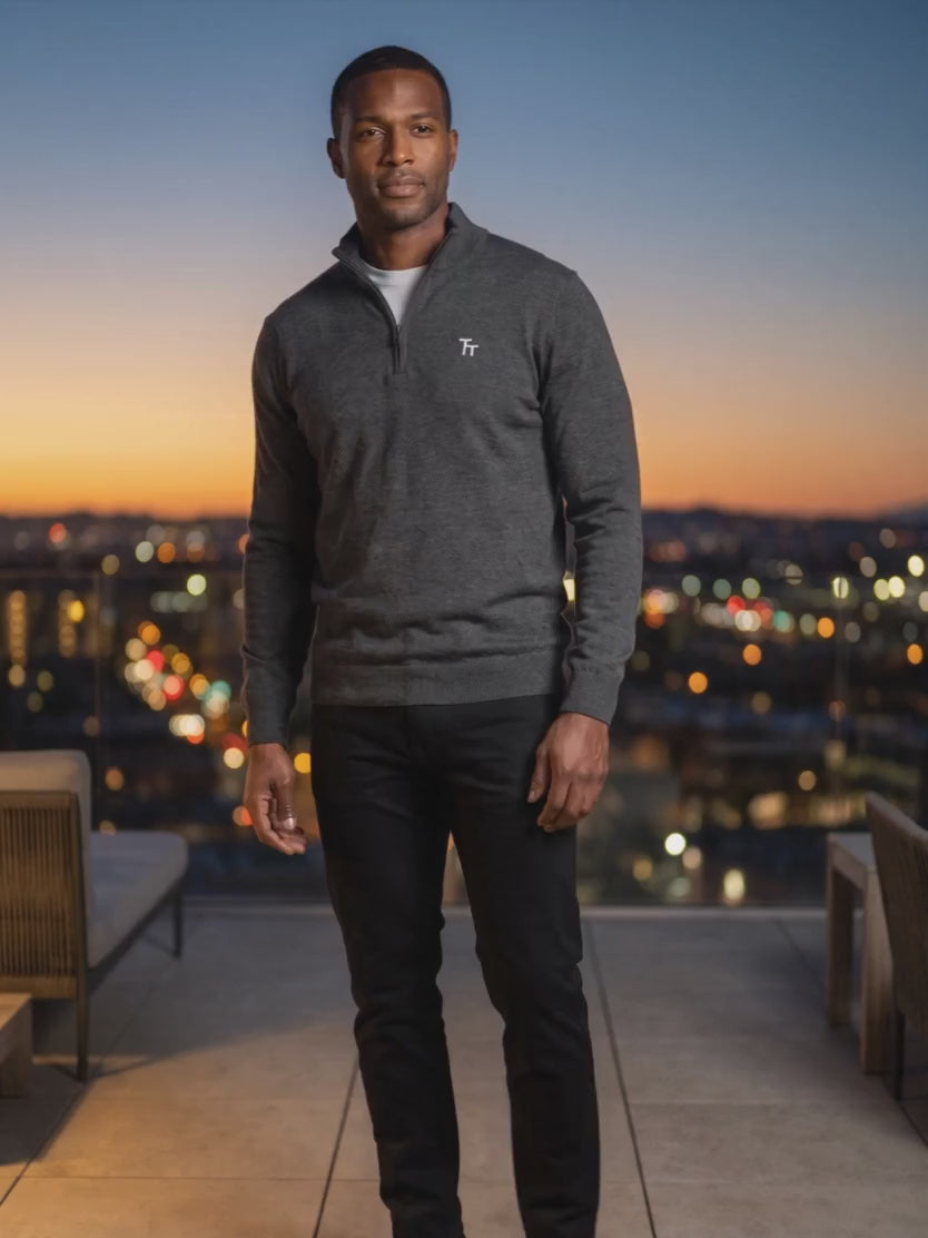 The London Chino in black, worn with a grey quarter-zip on a city rooftop