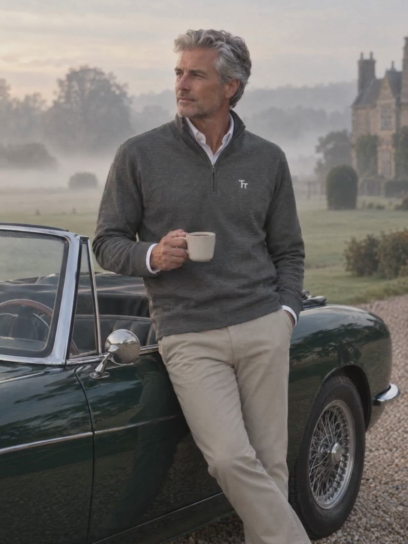 The Commit Quarter-Zip in dark grey, worn with tan chinos